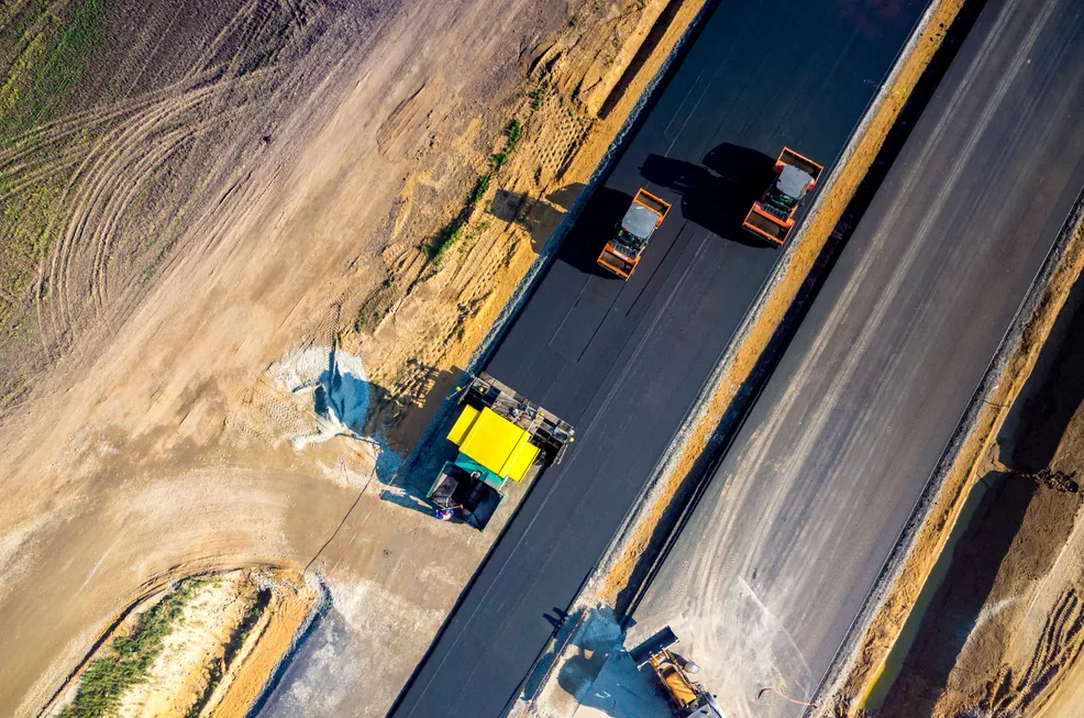 Pandangan dron kerja penurapan asfalt dengan paver dan roller / Drone view of asphalt paving works with paver and rollers